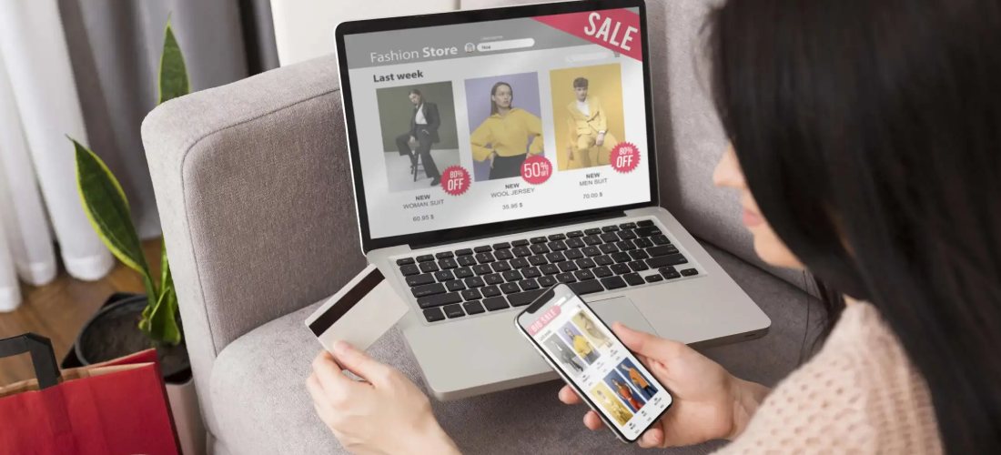 A shopper paying online with a card while browsing products on a laptop
